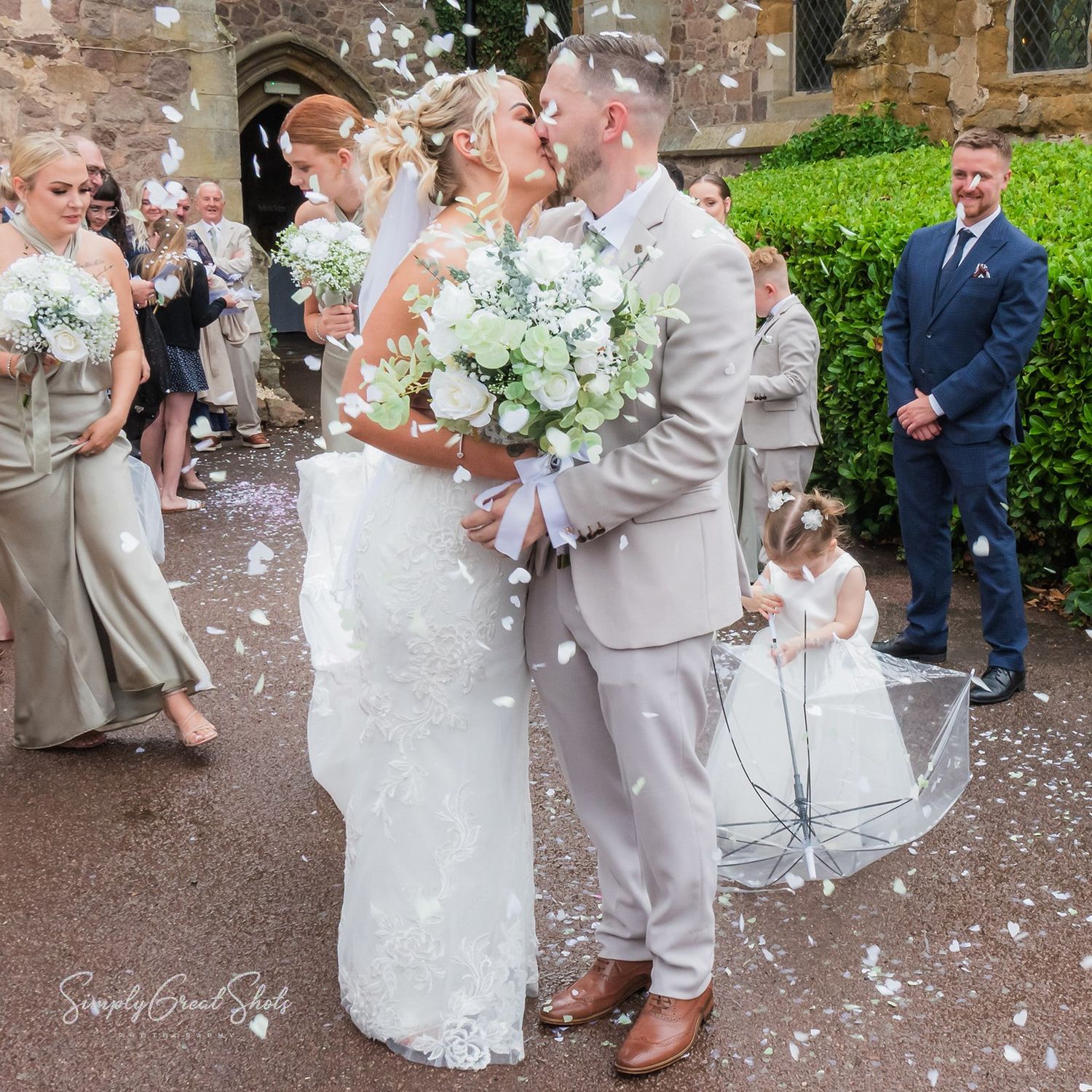 Wedding party celebrating with confetti on a stone pathway during an outdoor celebration.