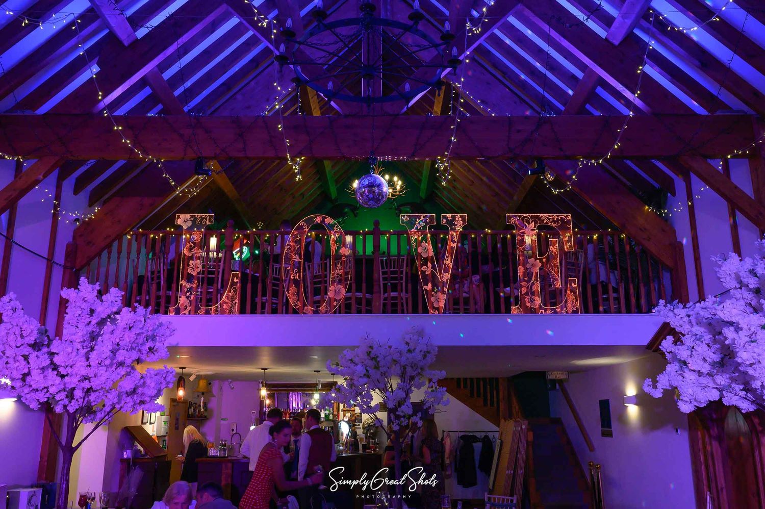 An illuminated Love sign on the balcony of Antlers bar at Winters Take Country Barn with subtle lighting captured by a wedding photographer