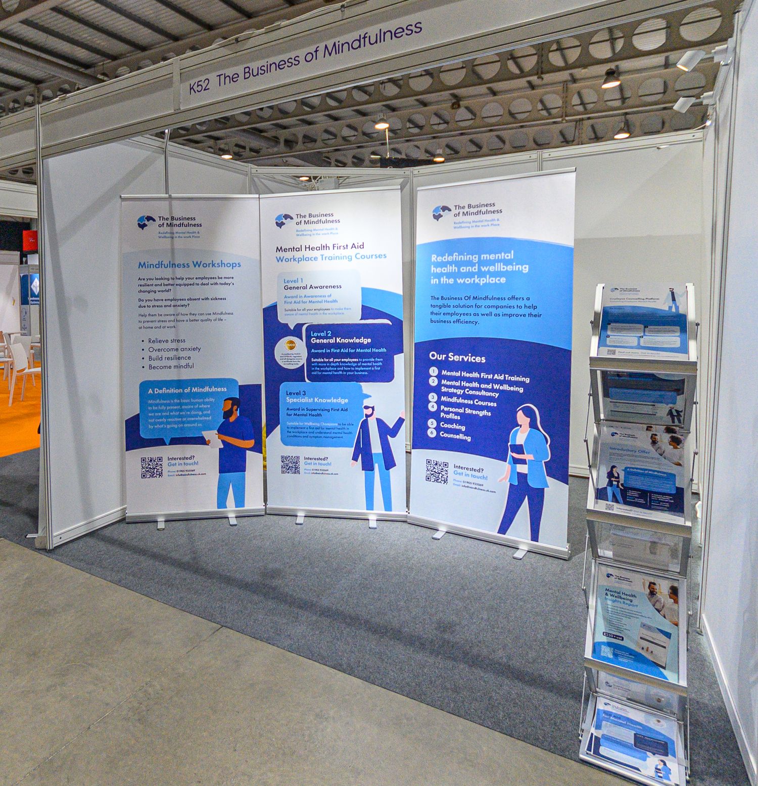 Trade show exhibition booth with blue and white banners displaying healthcare information and product literature holders.