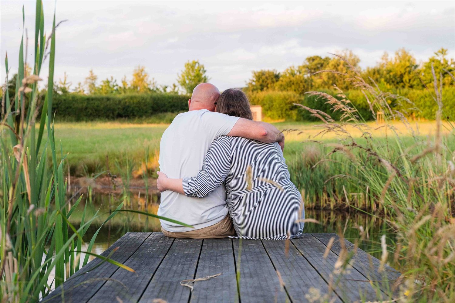 A happy couple look out towards the water on their pre-wedding photoshoot which was captured by a Warwickshire wedding photographer.