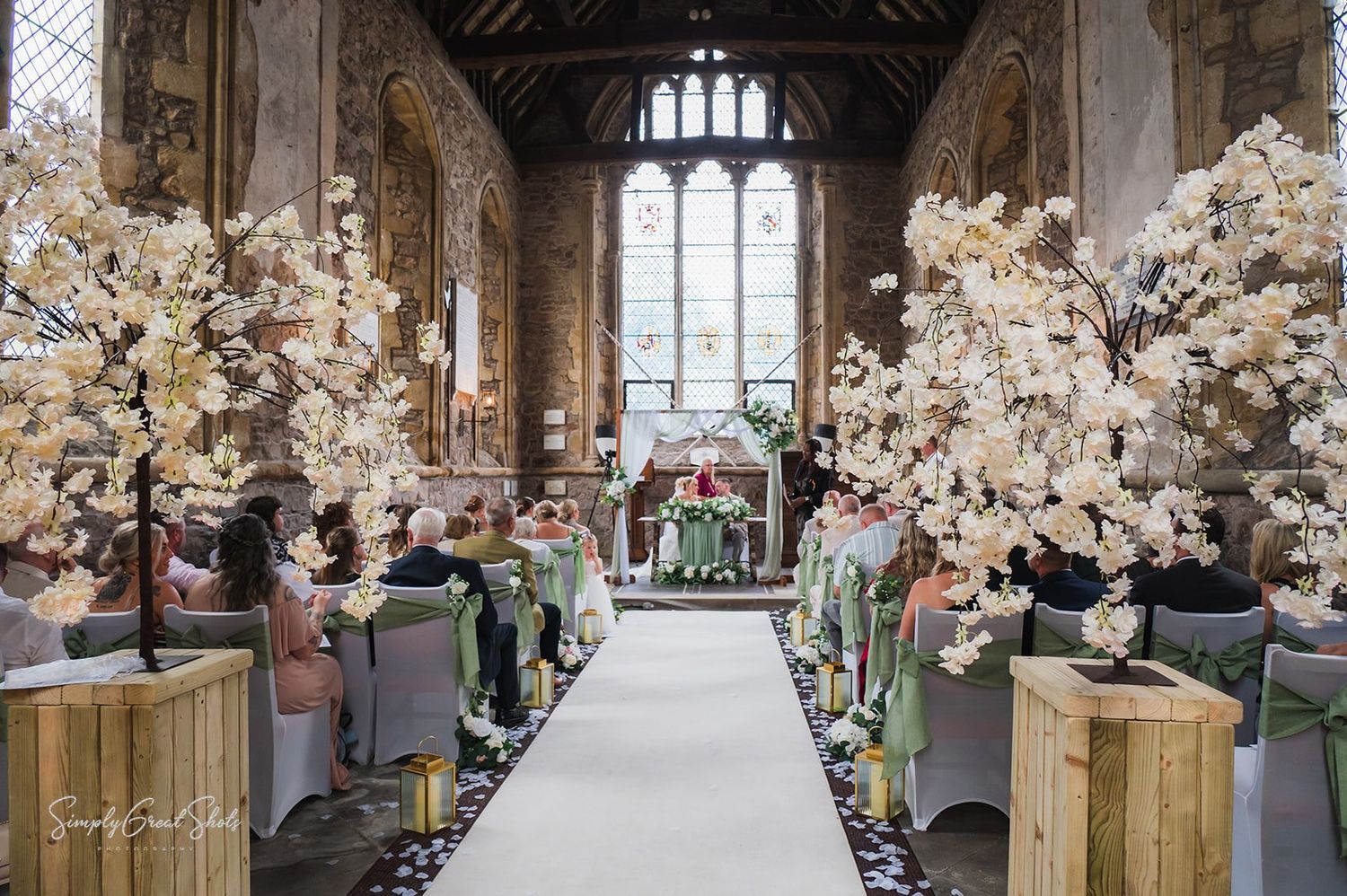 A beautiful chapel wedding ceremony setup with white cherry blossom trees lining the aisle creates an enchanting atmosphere.