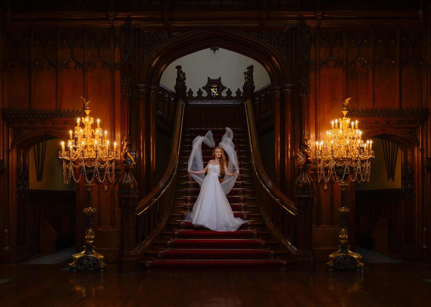 A stunning bride with a flowing trailing veil walks down the stairs.