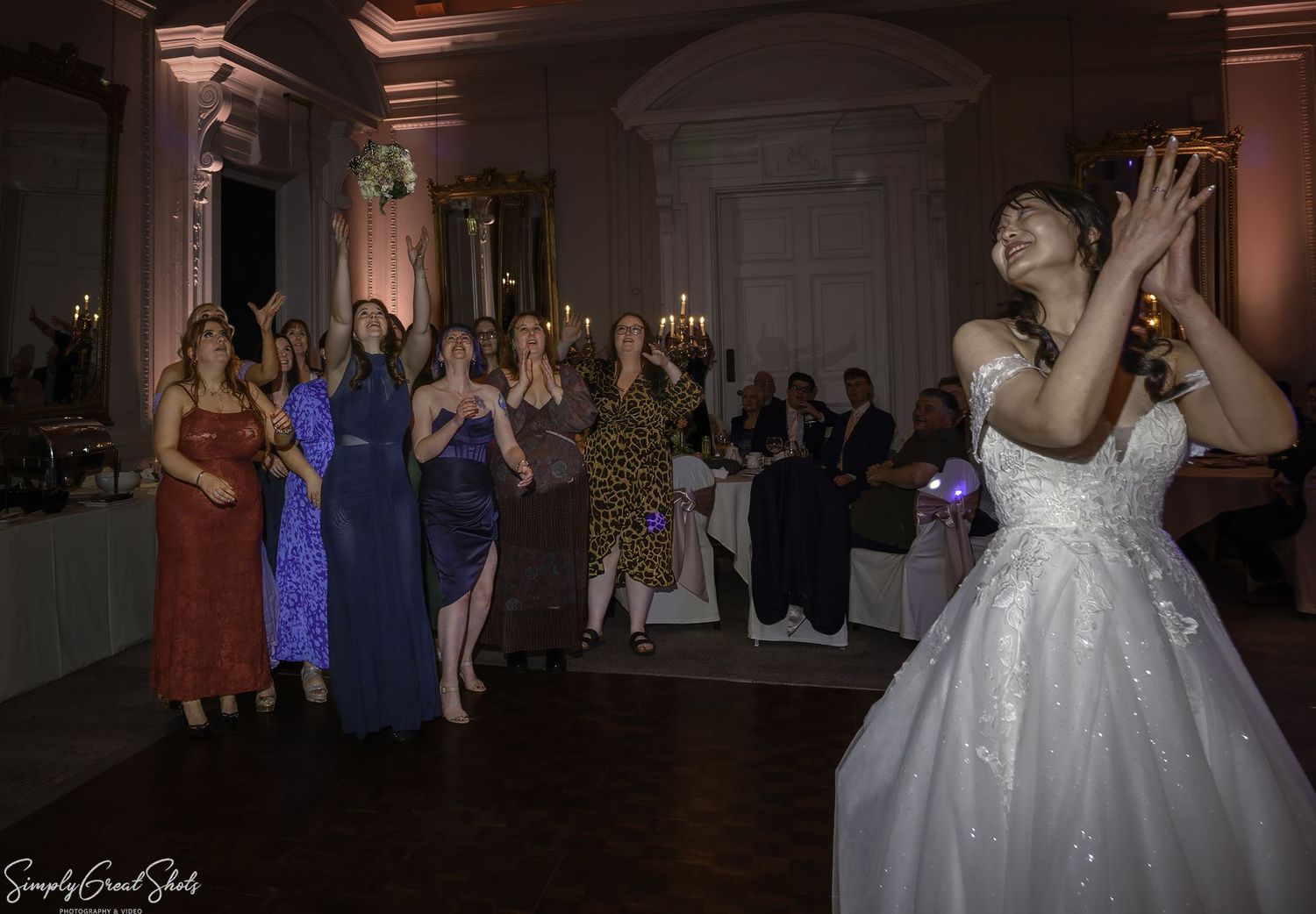 SimplyGreatShots capturing bride Minky throwing her bouquet to female guests in The Cloisters at Coombe Abbey.