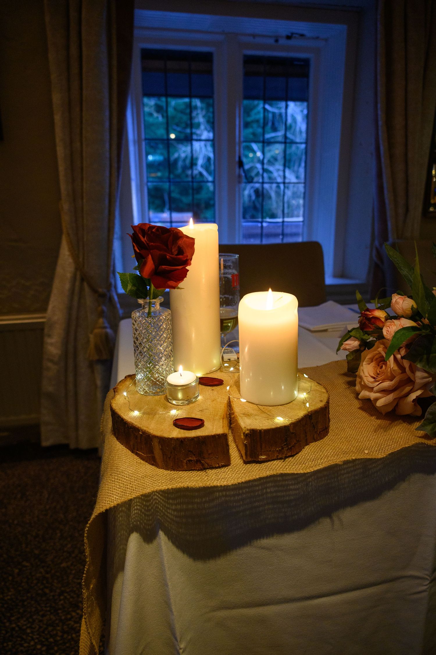 Rustic wedding table centerpiece with candles & red roses on a wooden windowsill at Saxon Mill – SimplyGreatShots Photography