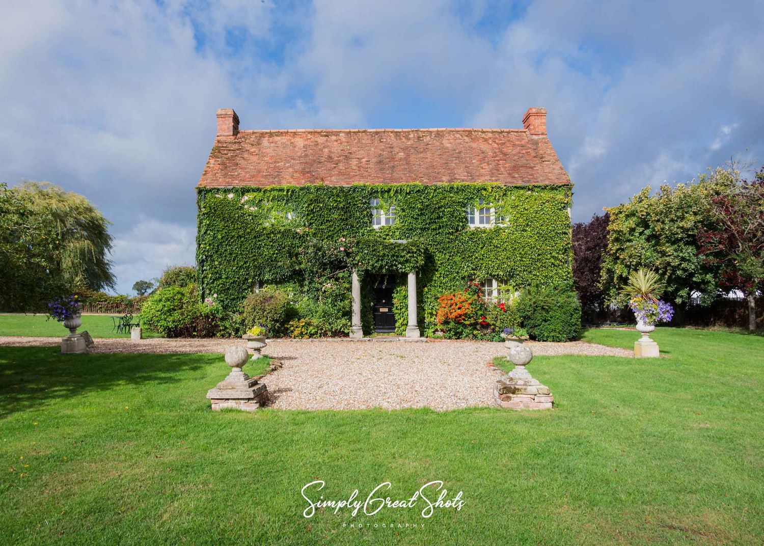 17th century rustic farmhouse at Winters Tale Country Barn wedding venue with green lawns and gardens surrounded by countryside landscape.