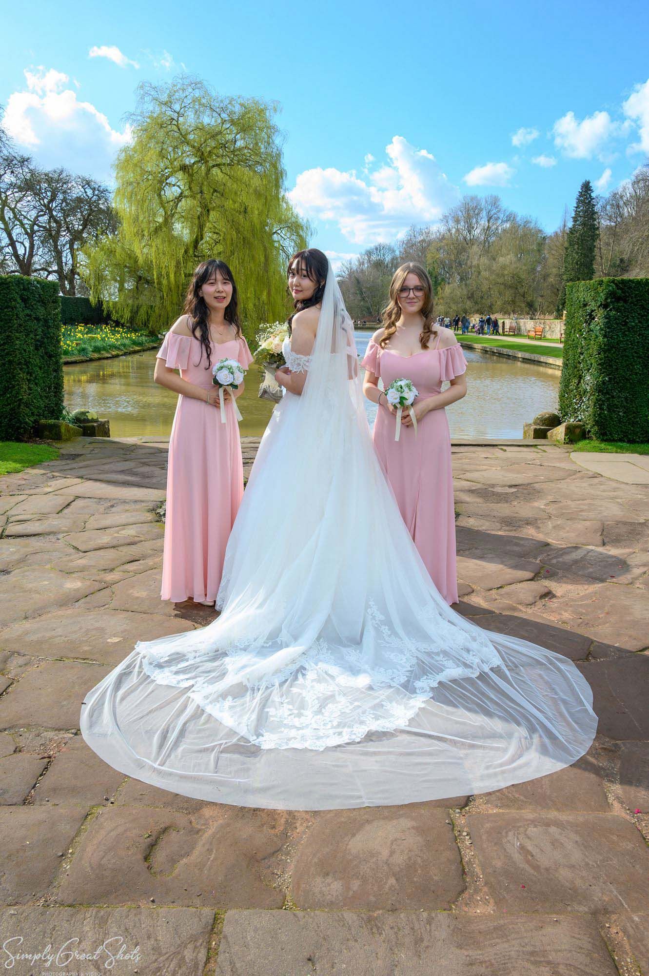 Coombe Abbey wedding photographer capturing bride Minky and bridesmaids in pink dresses by the lake.