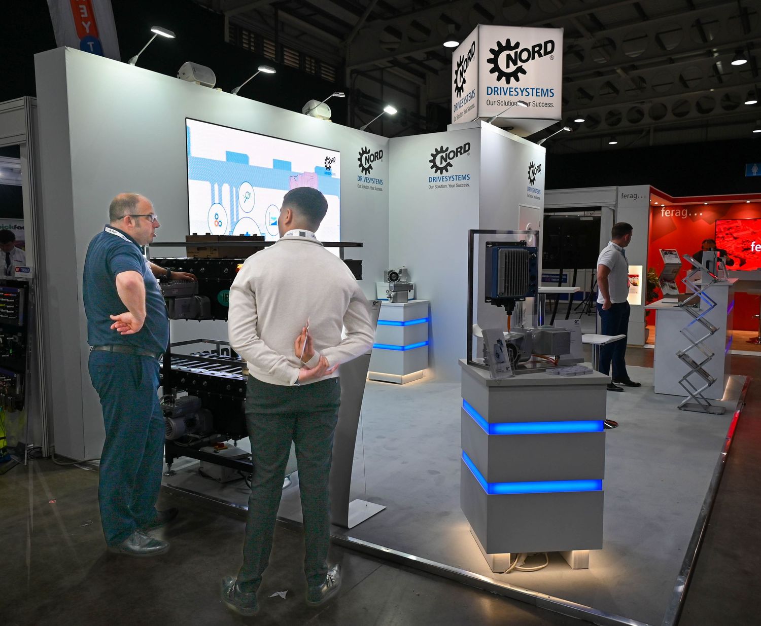Trade show booth display with two attendees viewing industrial equipment and machinery at a commercial exhibition.