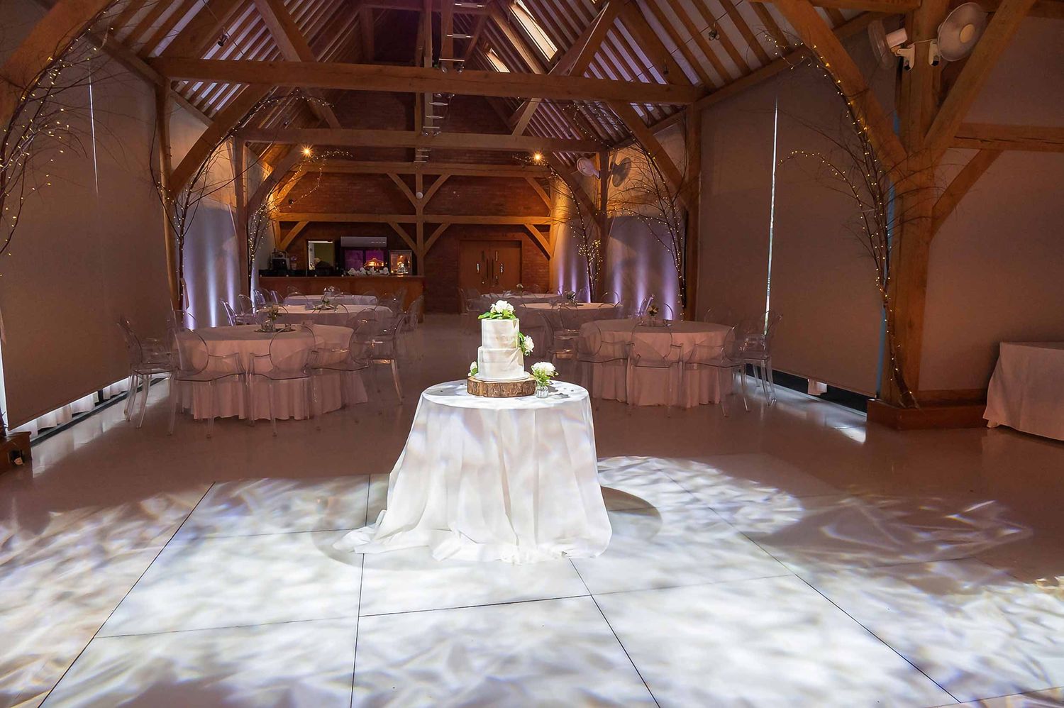 Redhouse Barn wedding photographer documenting wedding cake display in rustic barn with exposed beams