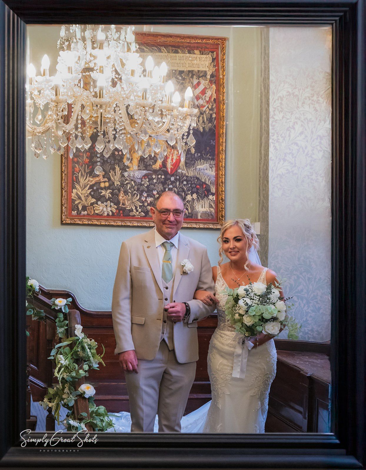 A father of the bride and bride walk down the staircase at Rothley Court wedding venue in Leicestershire.
