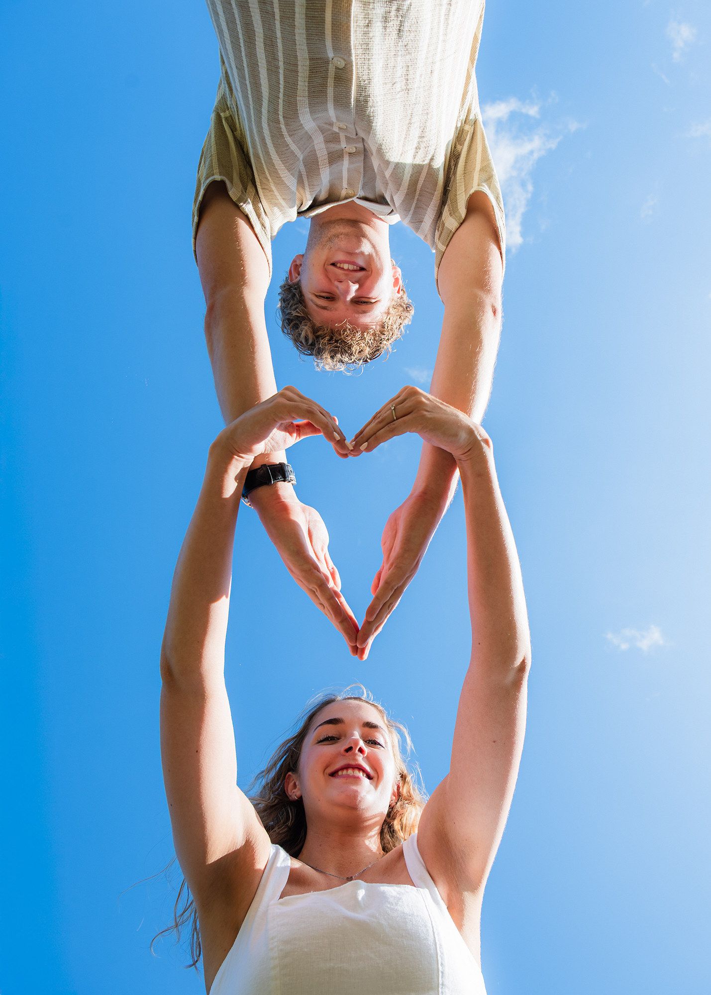 An engaged couple make a heart shape with their hands