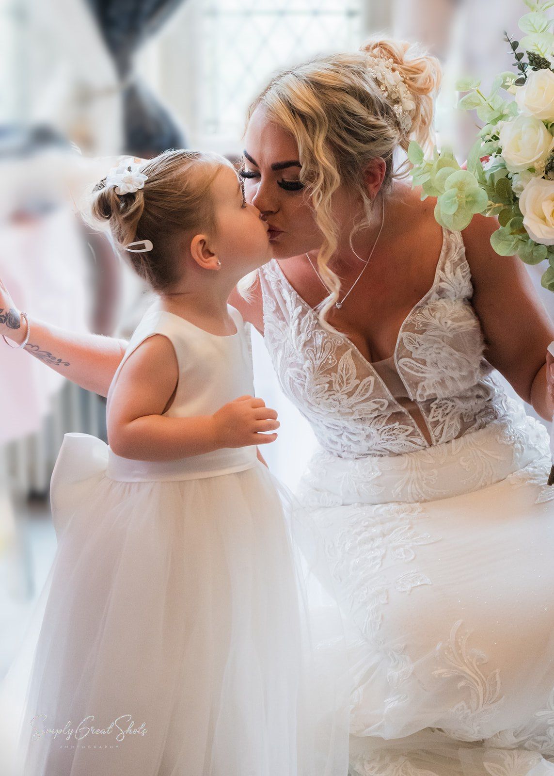 A bride kisses the flower girl (her daughter) prior to the wedding.