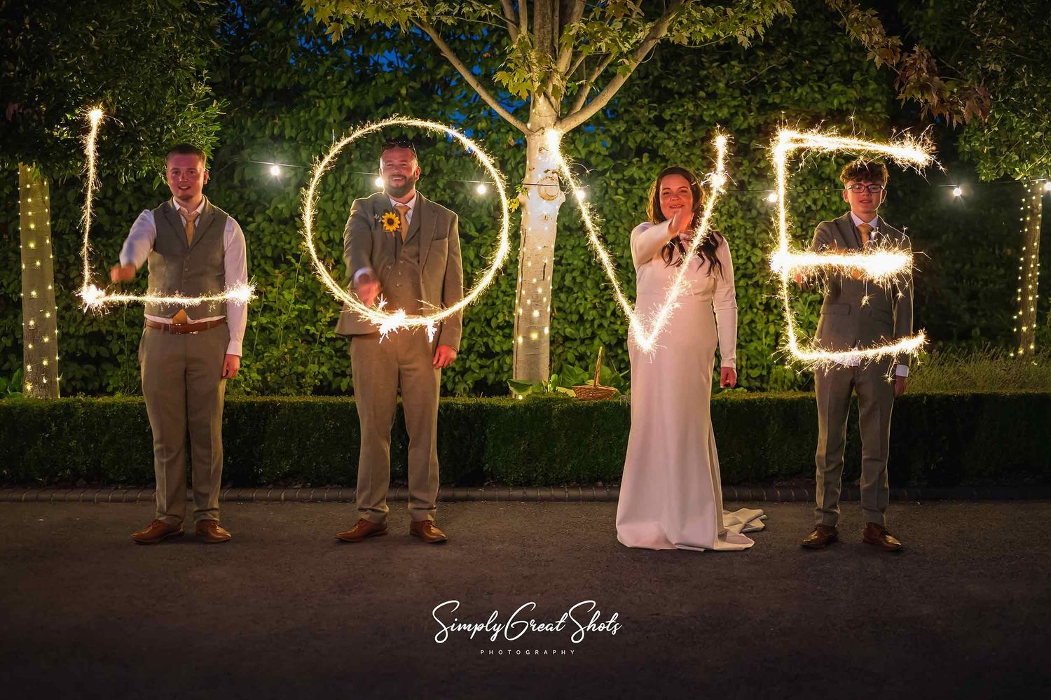 SimplyGreatShots Photography capture a couple on their wedding day with their two sons who between them create the word LOVE using sparklers