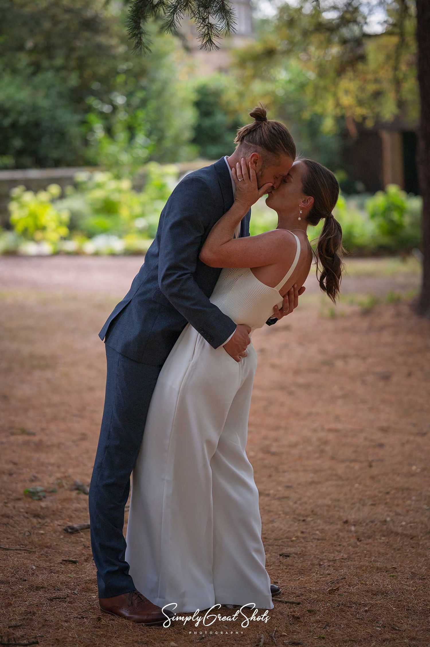 Hampton Manor wedding photographer captures husband and wife kissing whilst performing a throw-back pose in ancient woodlands