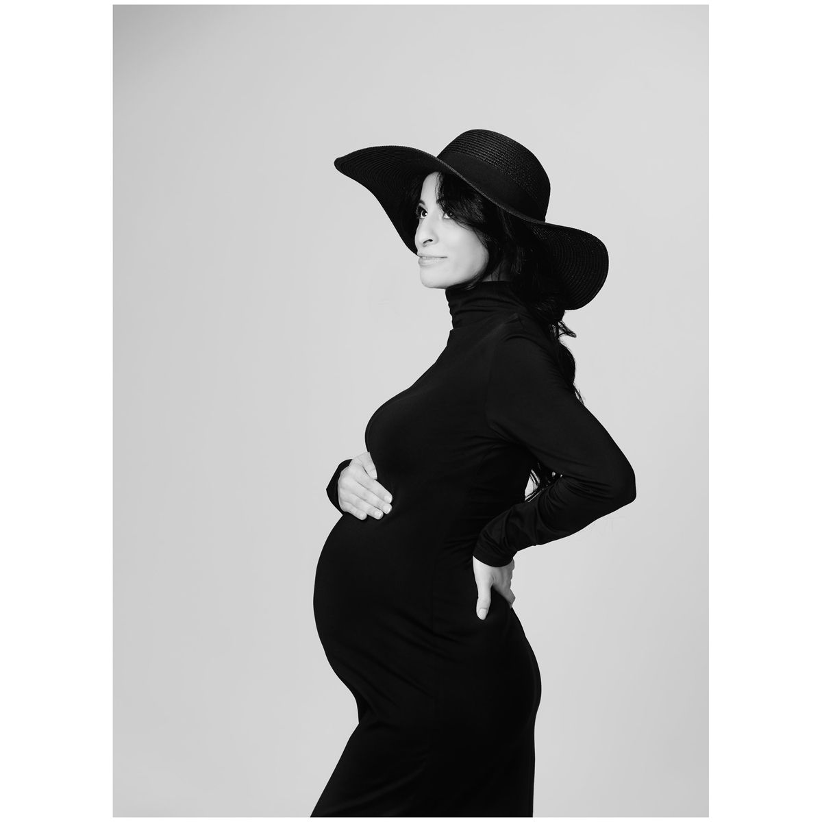 Black and White Maternity Photo by Austin Maternity Photographer featuring profile portrait of mom wearing wide brim hat and fitted dress.