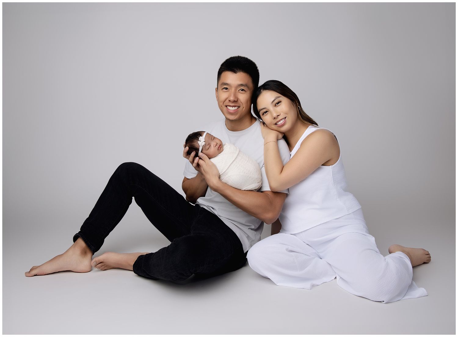 Newborn session family portrait by Austin Newborn Photographer VKP parents posed seated on the floor, mom leaned against dad's shoulder.