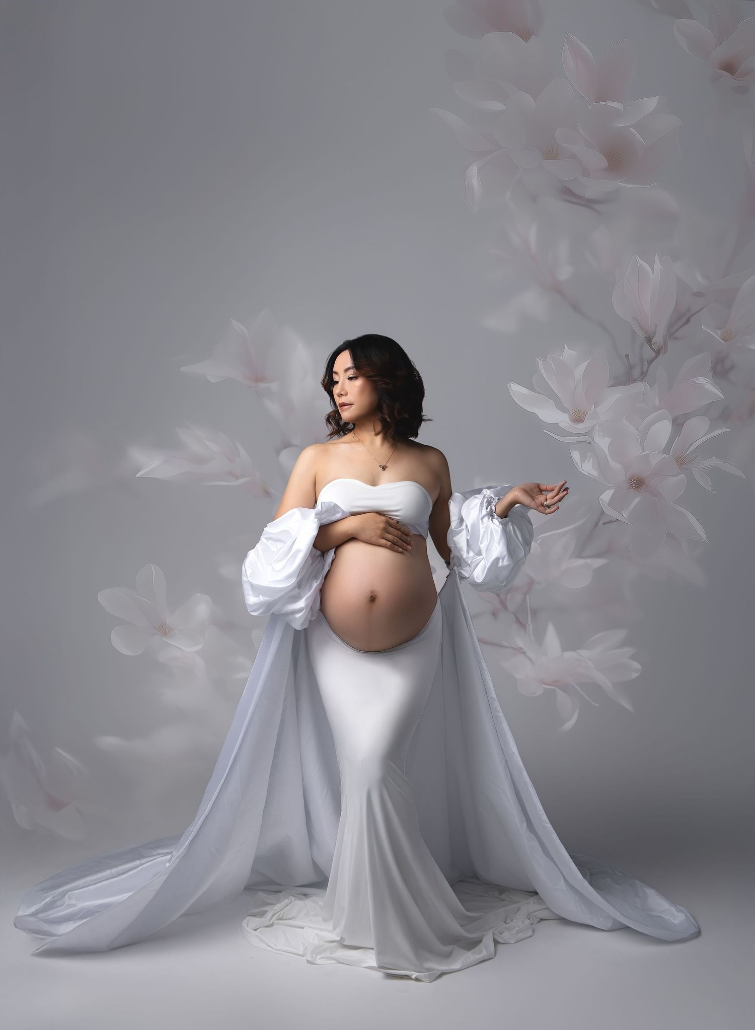 artistic austin maternity portrait featuring mom in white 2 piece dress wearing dramatic puffy sleeve satin cape on a soft floral background