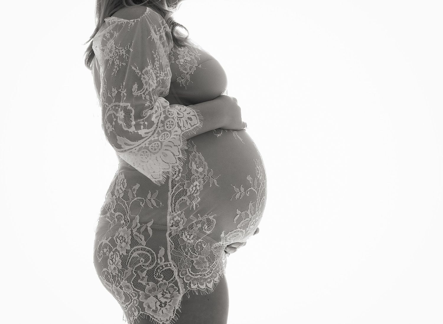Back lit close up of pregnant mom's belly posed on white background at Valerie Kay Photography Maternity Studio.