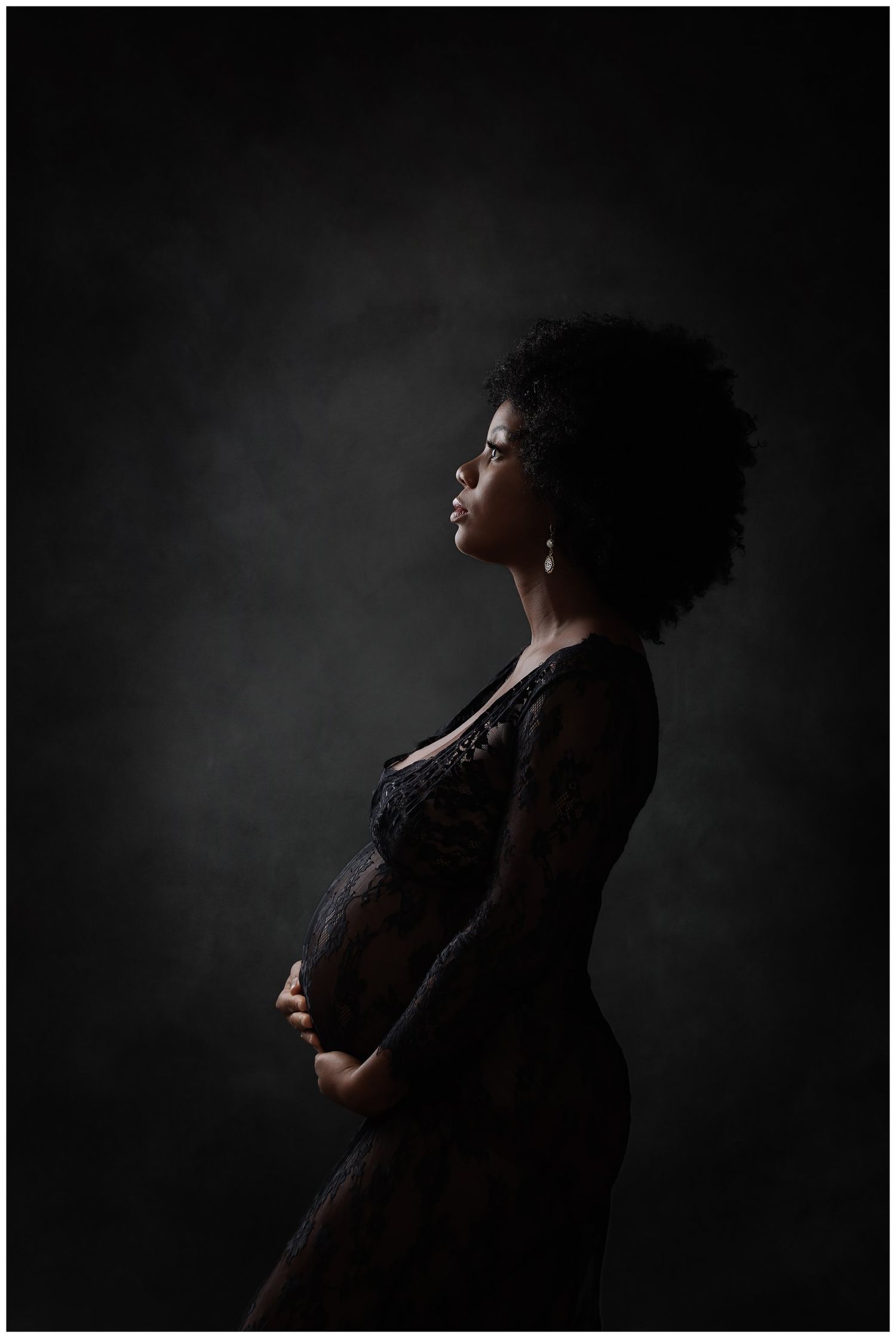 AWard winning maternity portrait featuring a low key dark background silhoutte.