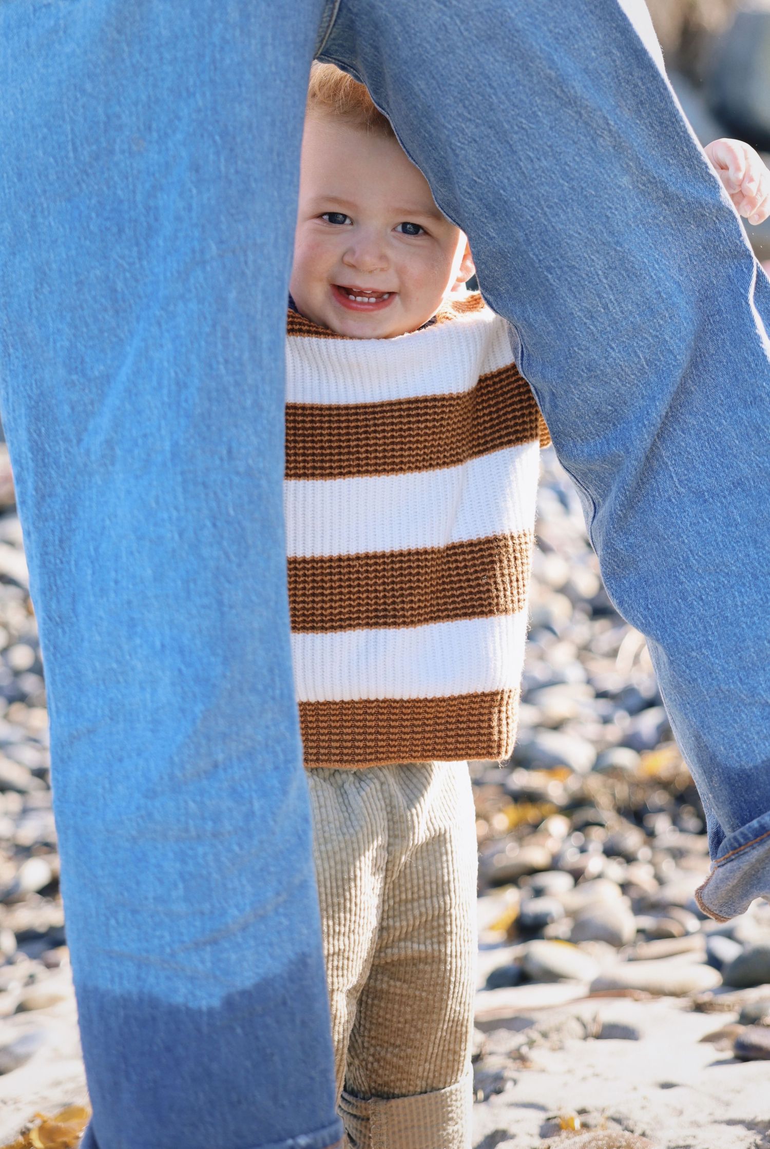 toddler peeking through mom's blue jeans