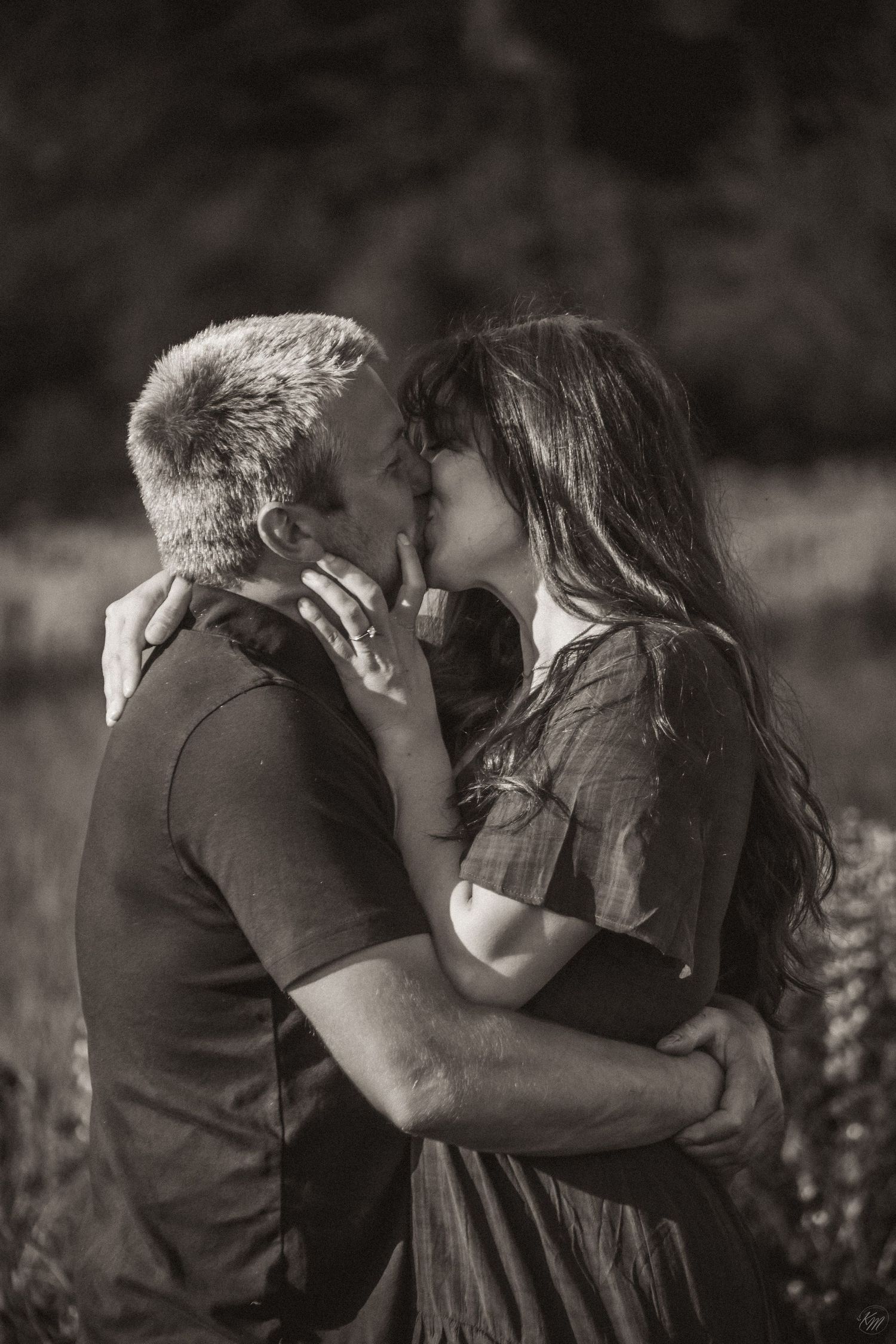 Black and white romantic photograph of a couple sharing an intimate kiss outdoors in a natural setting in Alaska.