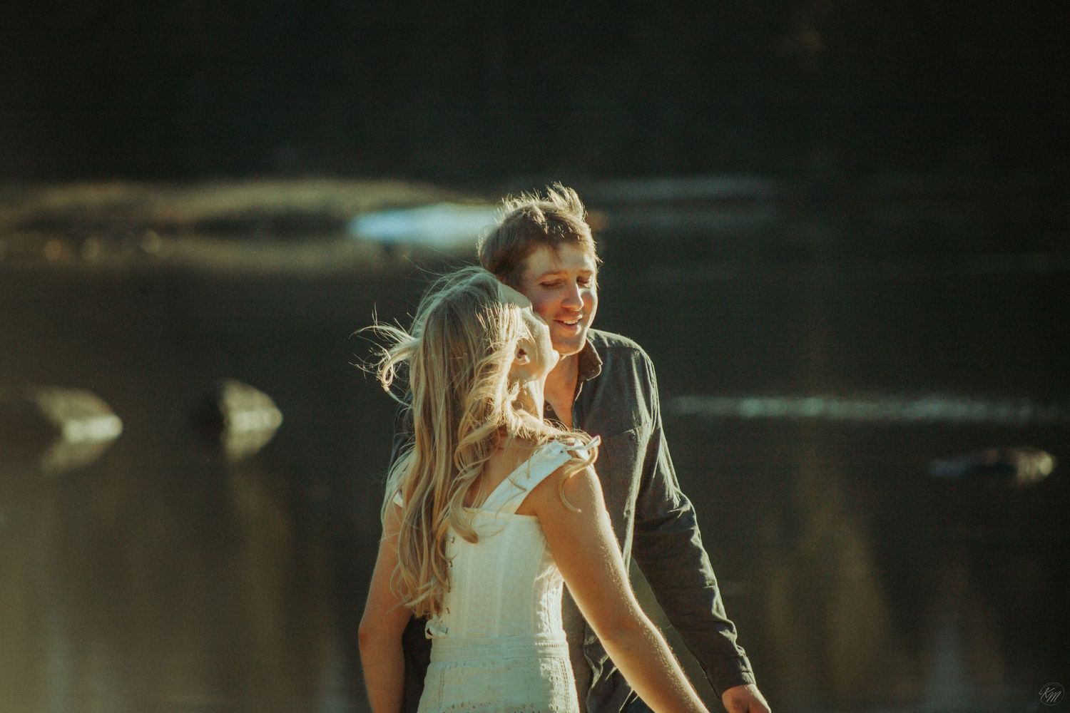 Wedding couple sharing an intimate moment by a serene lake at sunset in golden light in Southeast Alaska.
