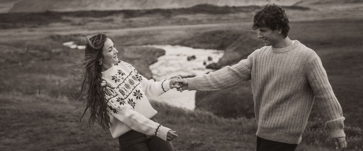 A black and white photo captures a couple in an intimate moment on a scenic hillside for Iceland Engagement.