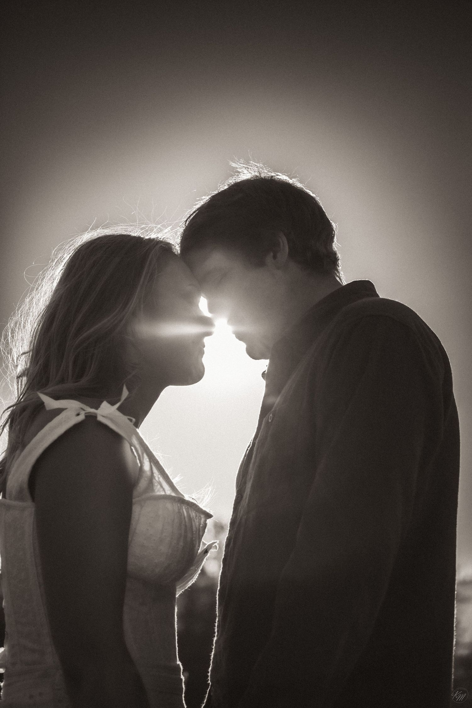 A romantic silhouette of a couple touching foreheads with sunlight creating a backlit glow behind them in Southeast Alaska