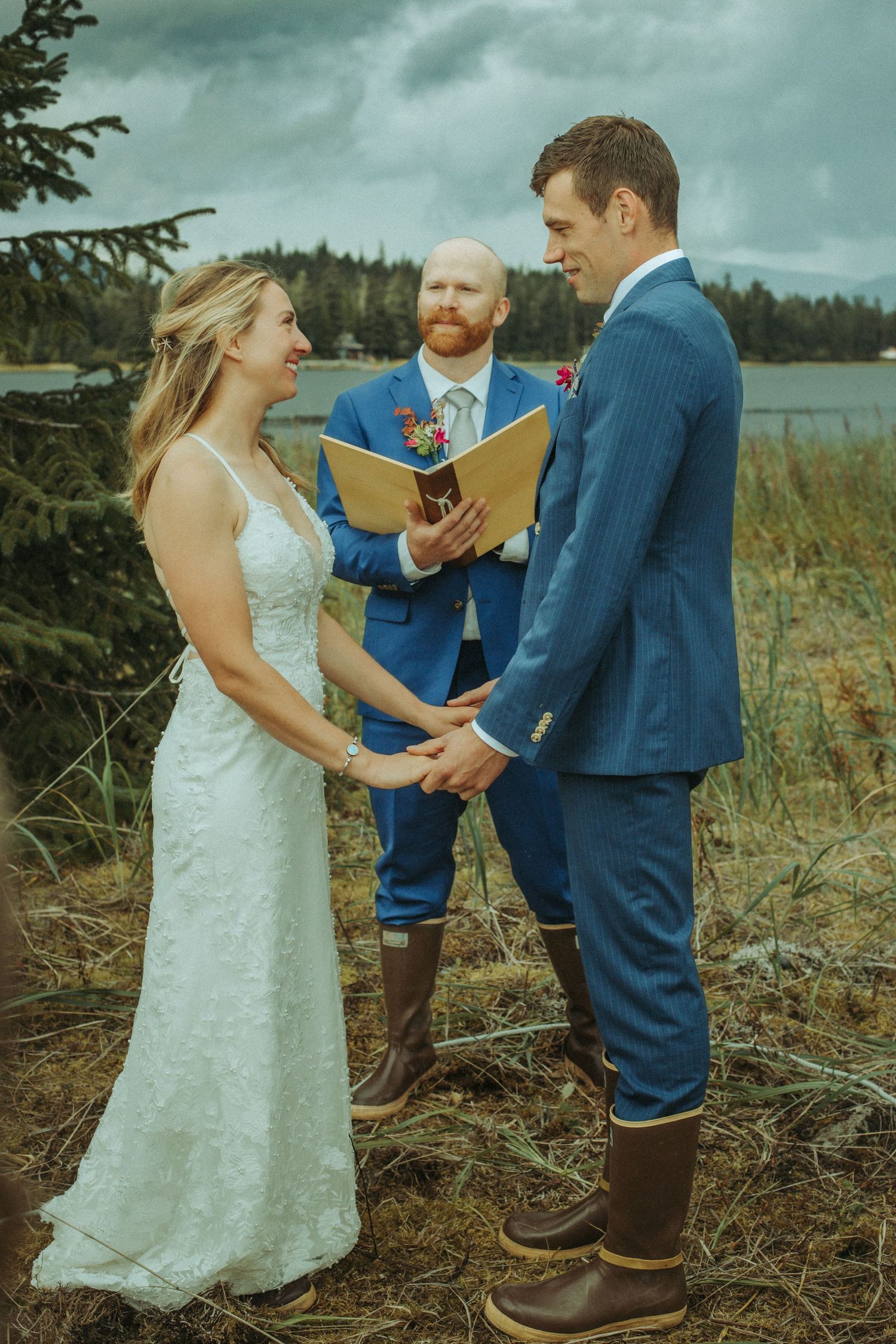 Rustic outdoor wedding ceremony takes place on a rugged hillside with water views in Alaska.