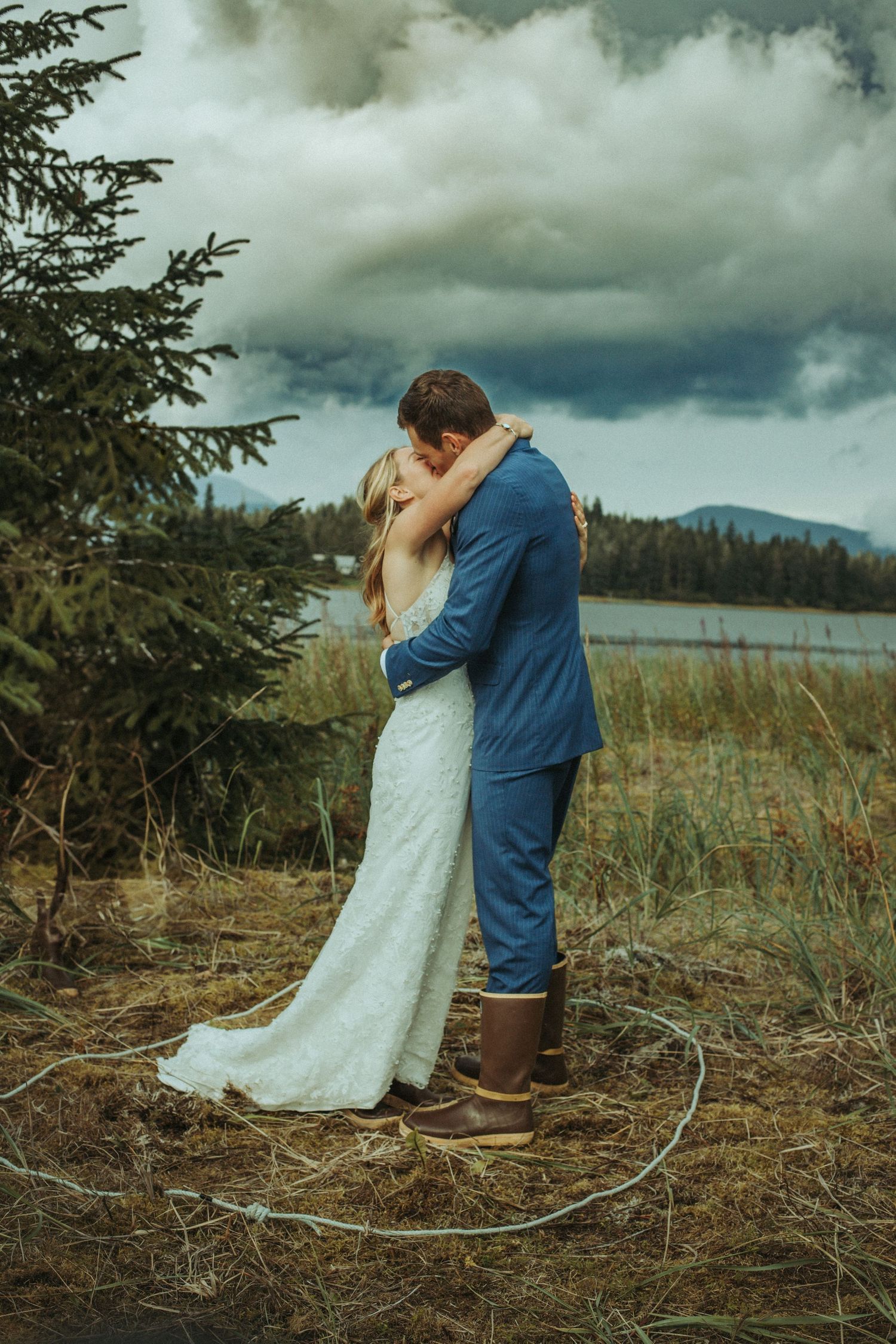 Romantic elopement wedding moment captured on a scenic coastal beach under stormy skies in Alaska.