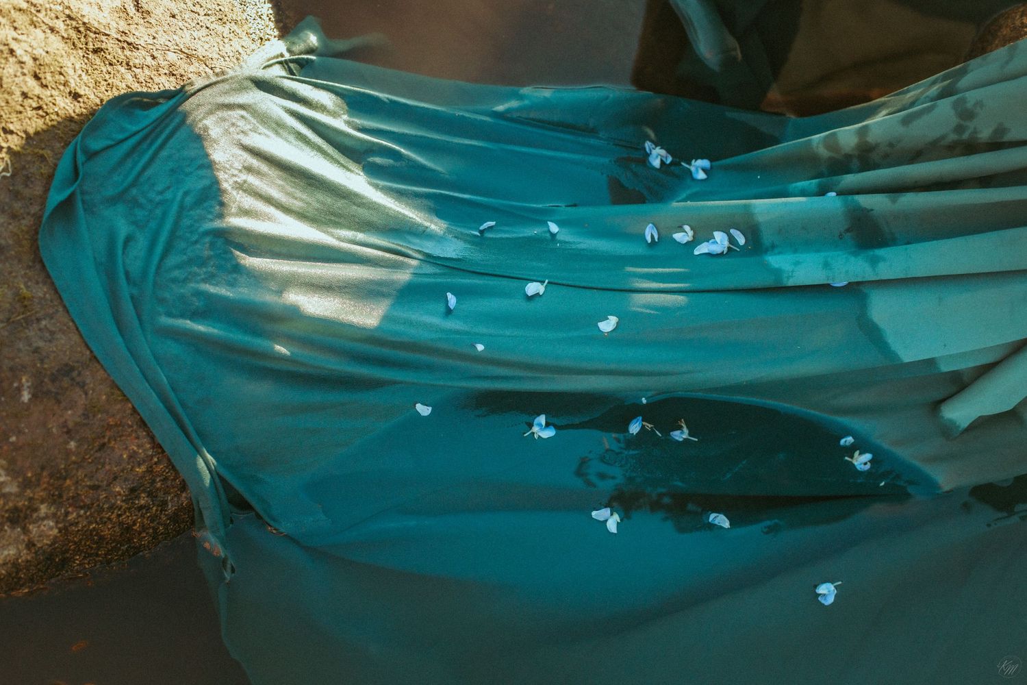 Close-up of teal fabric with water droplets creating a reflective pattern.