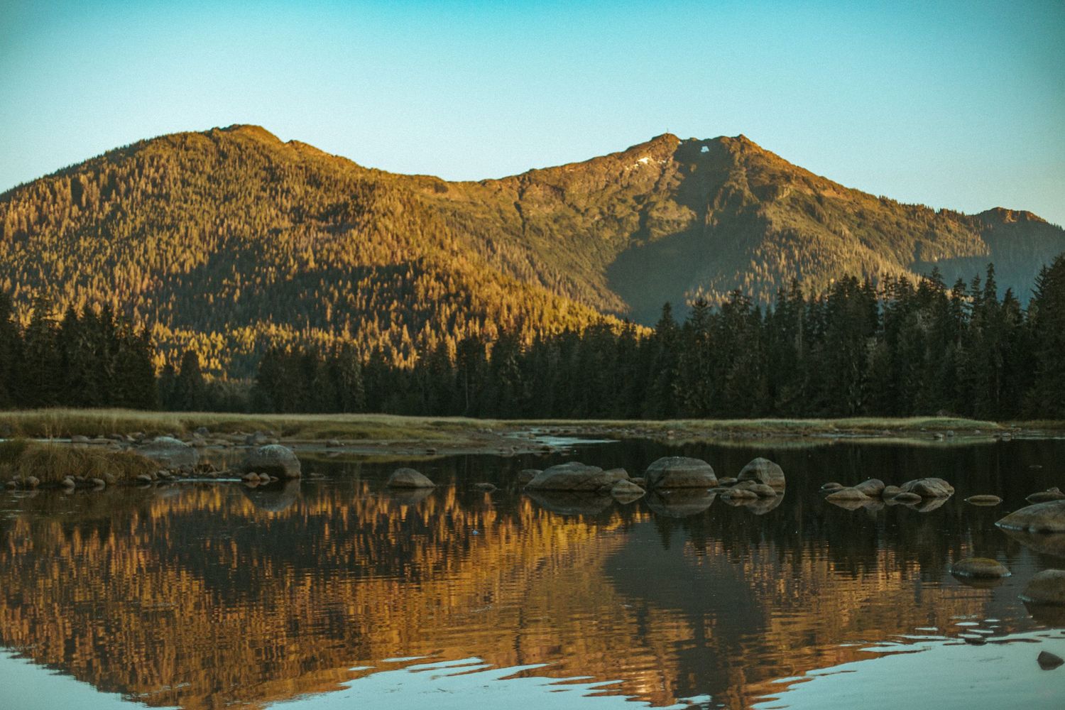 Mountain peak reflecting in calm lake waters during golden hour.