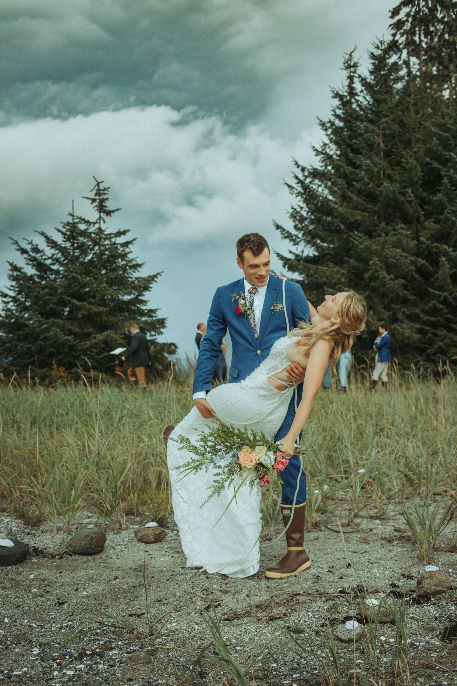 Playful elopement photography on a rocky coastal beach with evergreen backdrop in Alaska.
