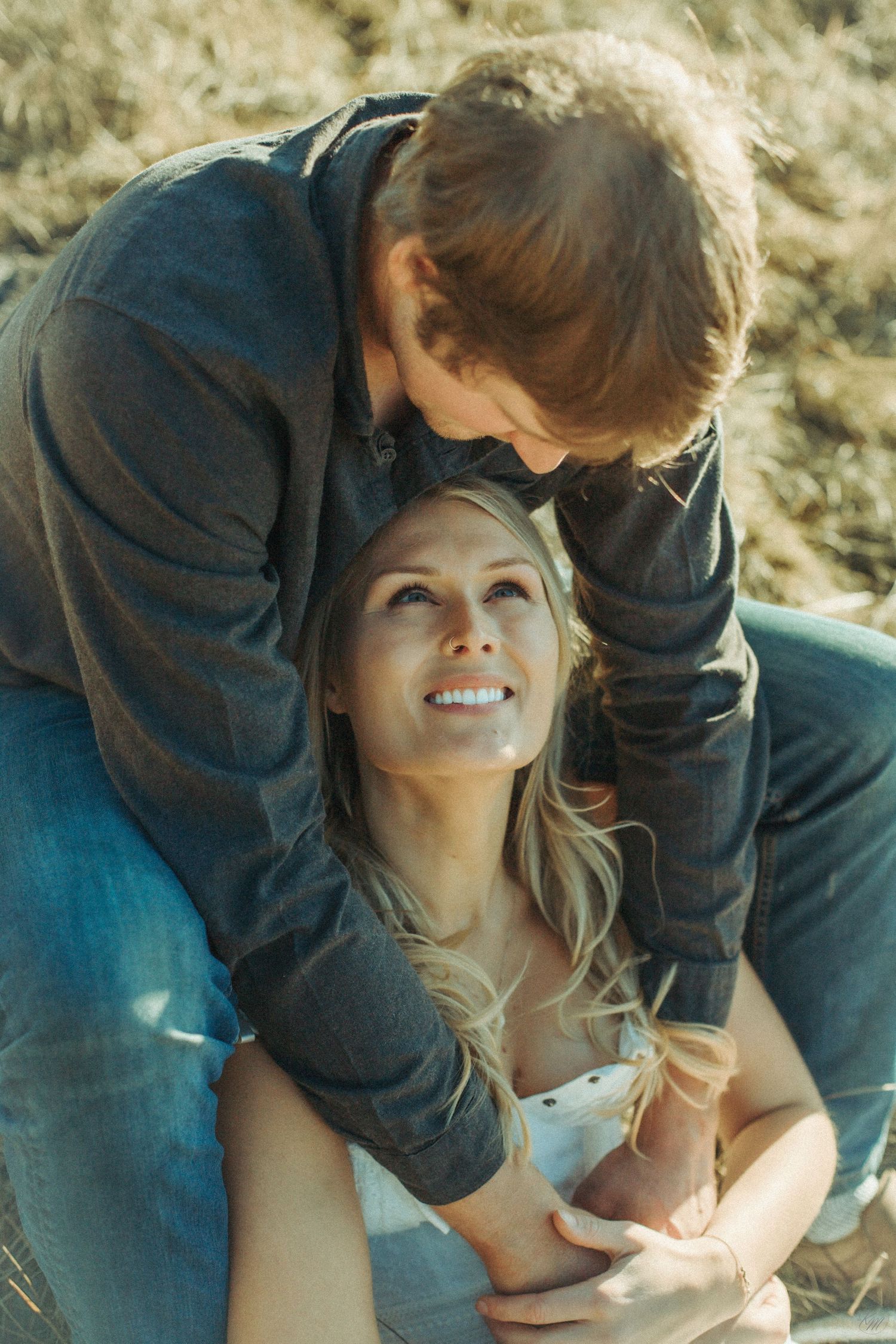 A tender romantic moment between a couple outdoors with warm sunlight and intimate expressions in Southeast Alaska.