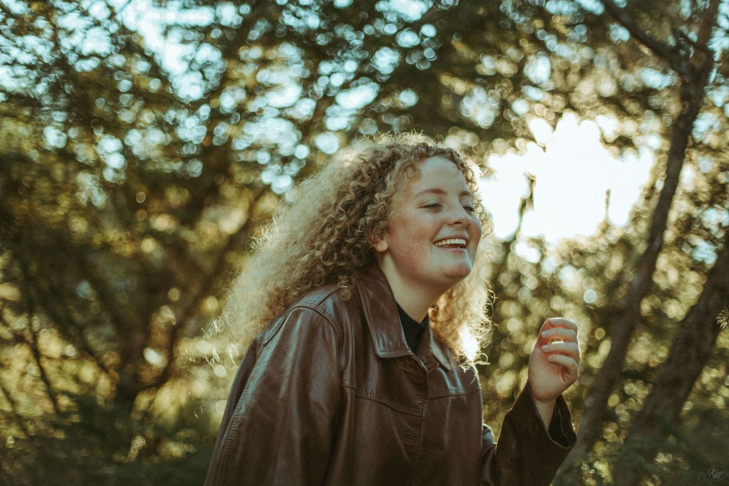 Candid laughing moment captured in warm sunlight with forest backdrop.