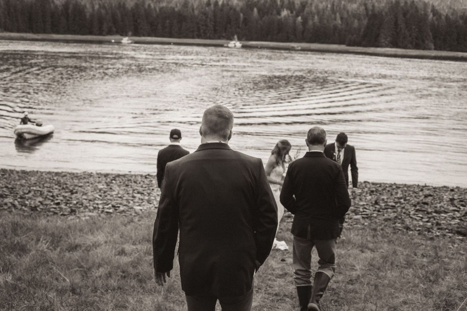 Wedding guests walking down towards a lakeside gathering at dusk.
