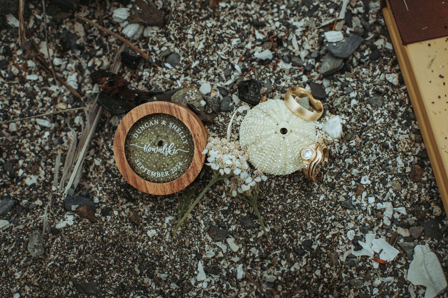 A broken vintage compass lying among scattered beach rocks and sand for a unique flat lay.