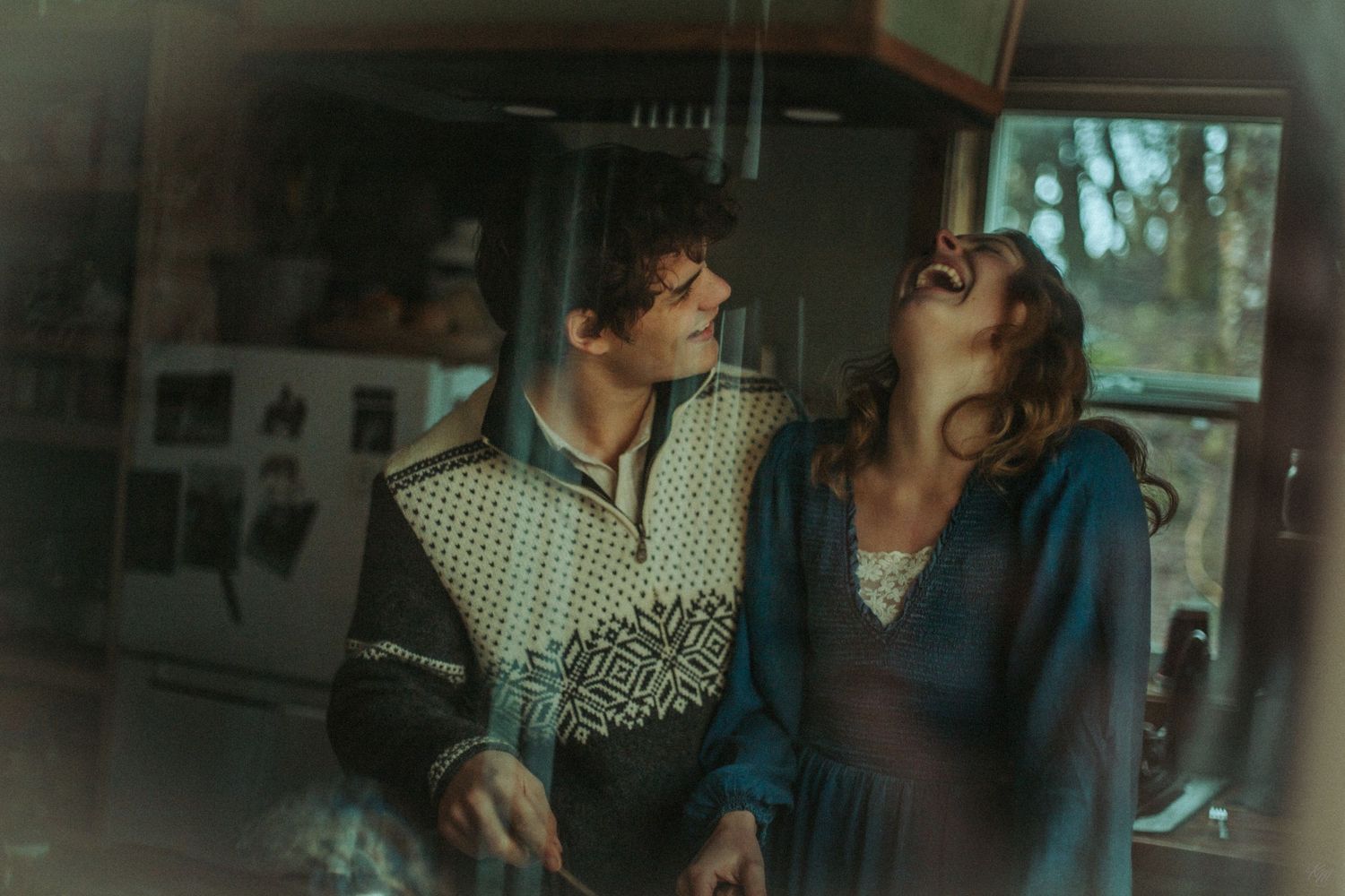 A retro-styled atmospheric image showing a couple sharing a laughing moment together in a vintage interior setting in Southeast Alaska.