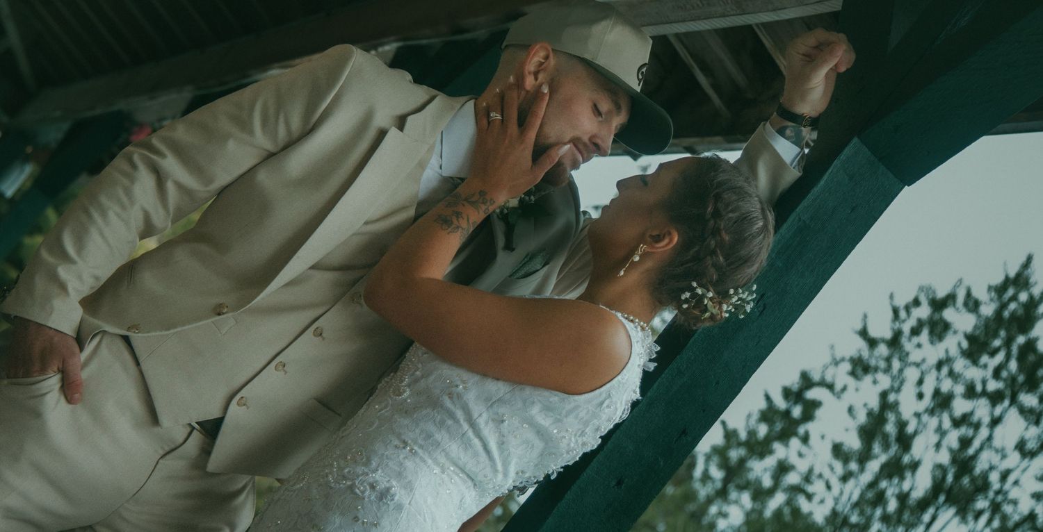 Bride and groom share a passionate kiss under a gazebo at their outdoor Alaska wedding ceremony.