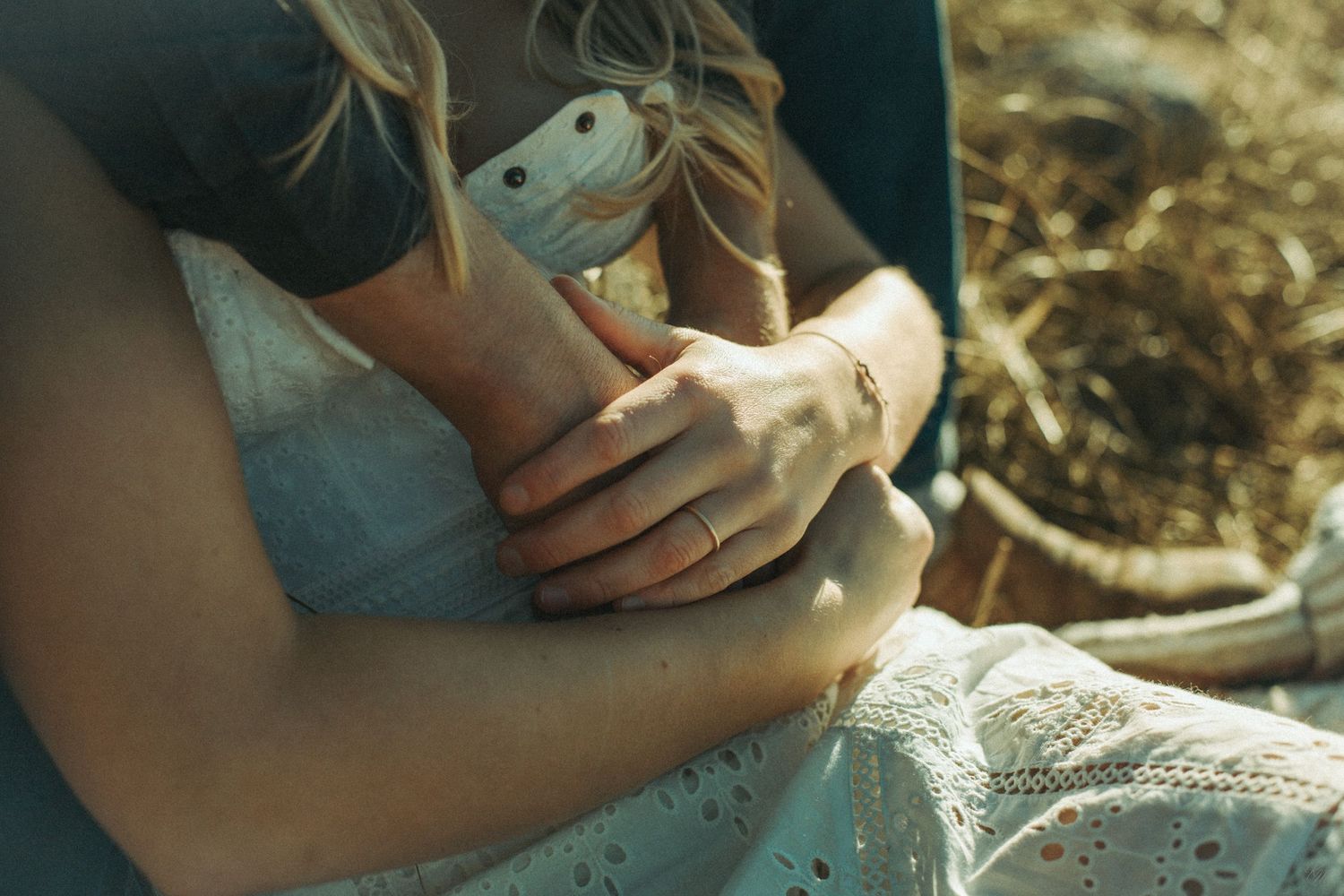 Close-up shot of hands holding engagement rings  against a dress in natural sunlight in Southeast Alaska..