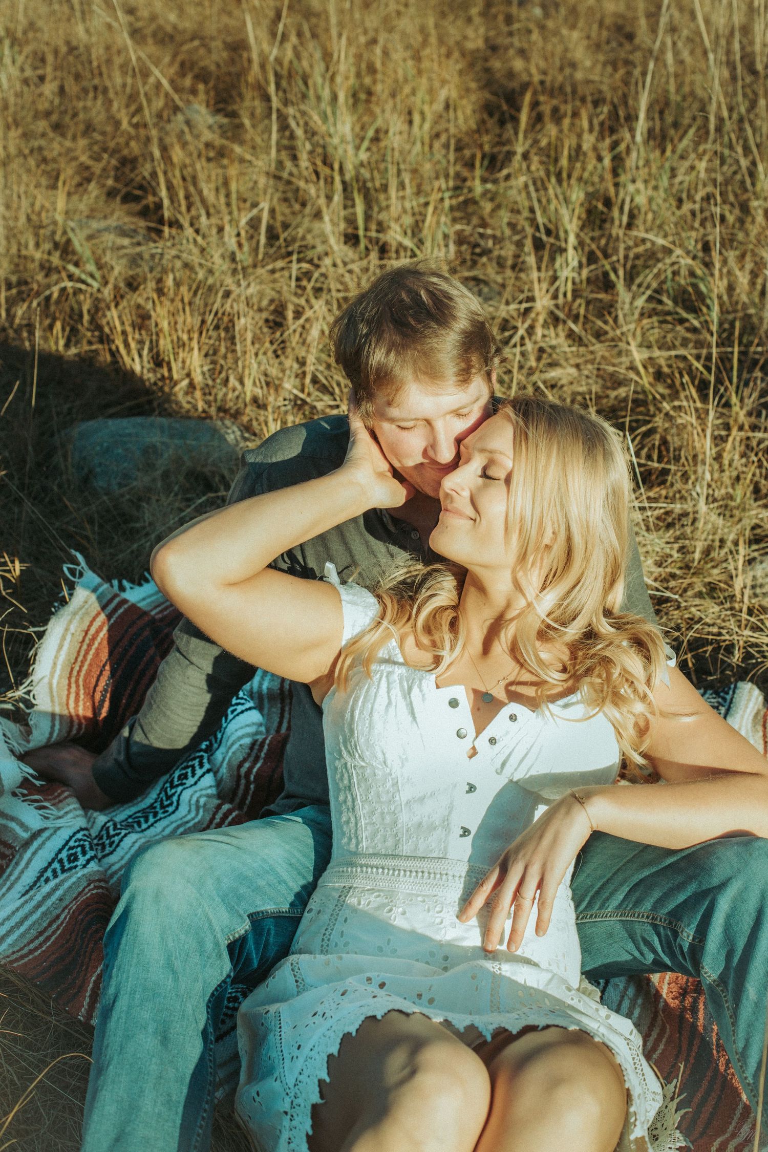A sweet romantic moment on a blanket in a field of golden grass during sunset in Southeast Alaska.