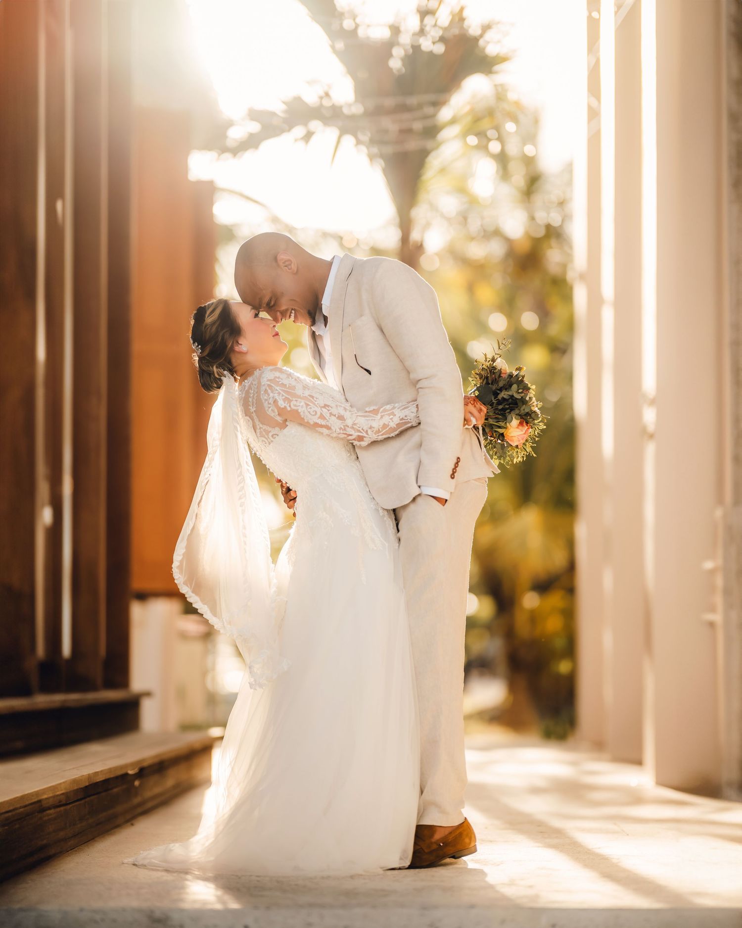 Sunlit wedding portraits captured in an elegant colonnade with dramatic lighting.