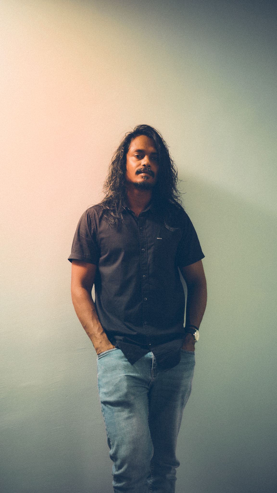 Portrait of person in dark shirt against gradient background.