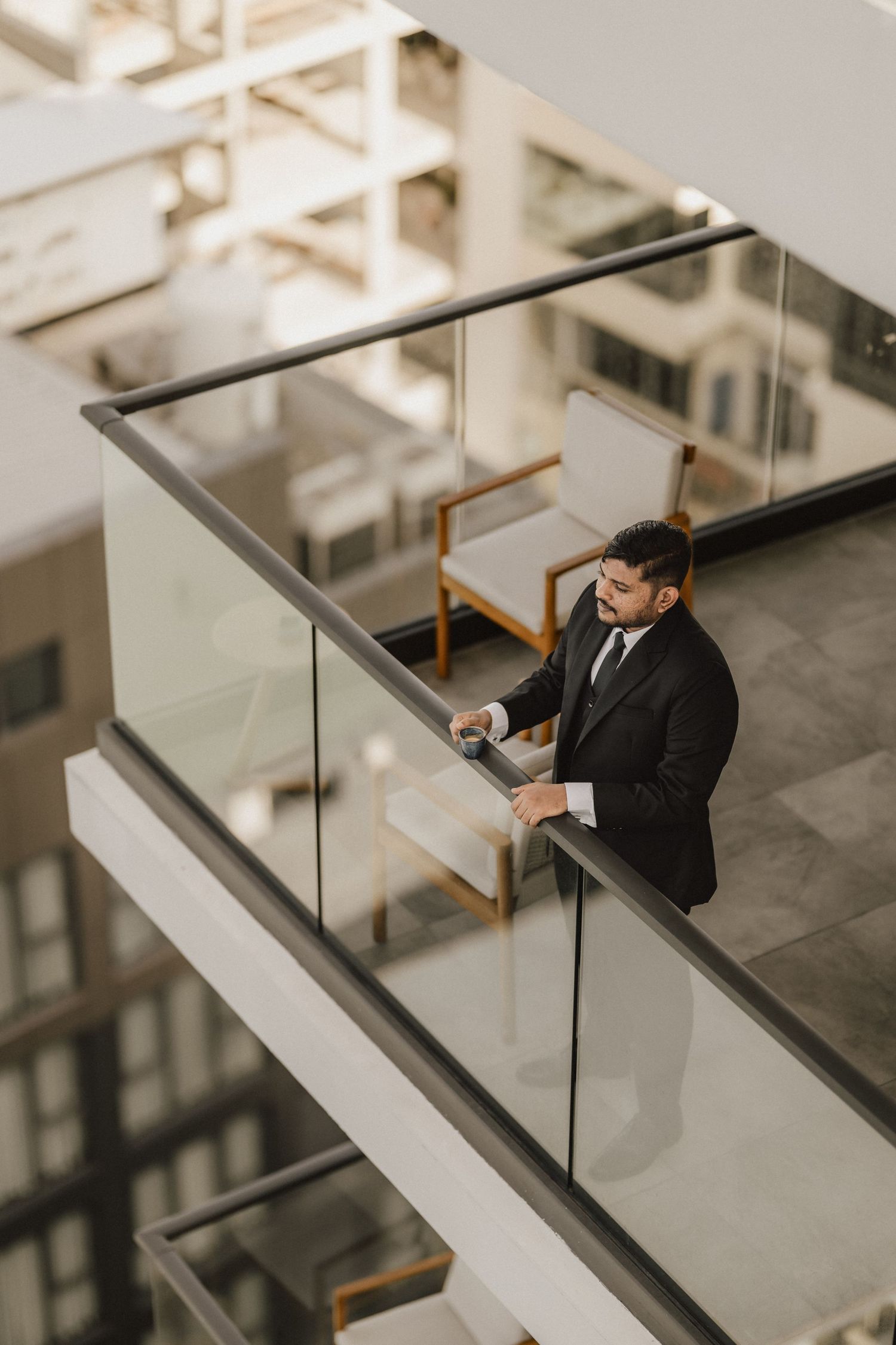 Architectural view of person looking over modern glass balcony railing.