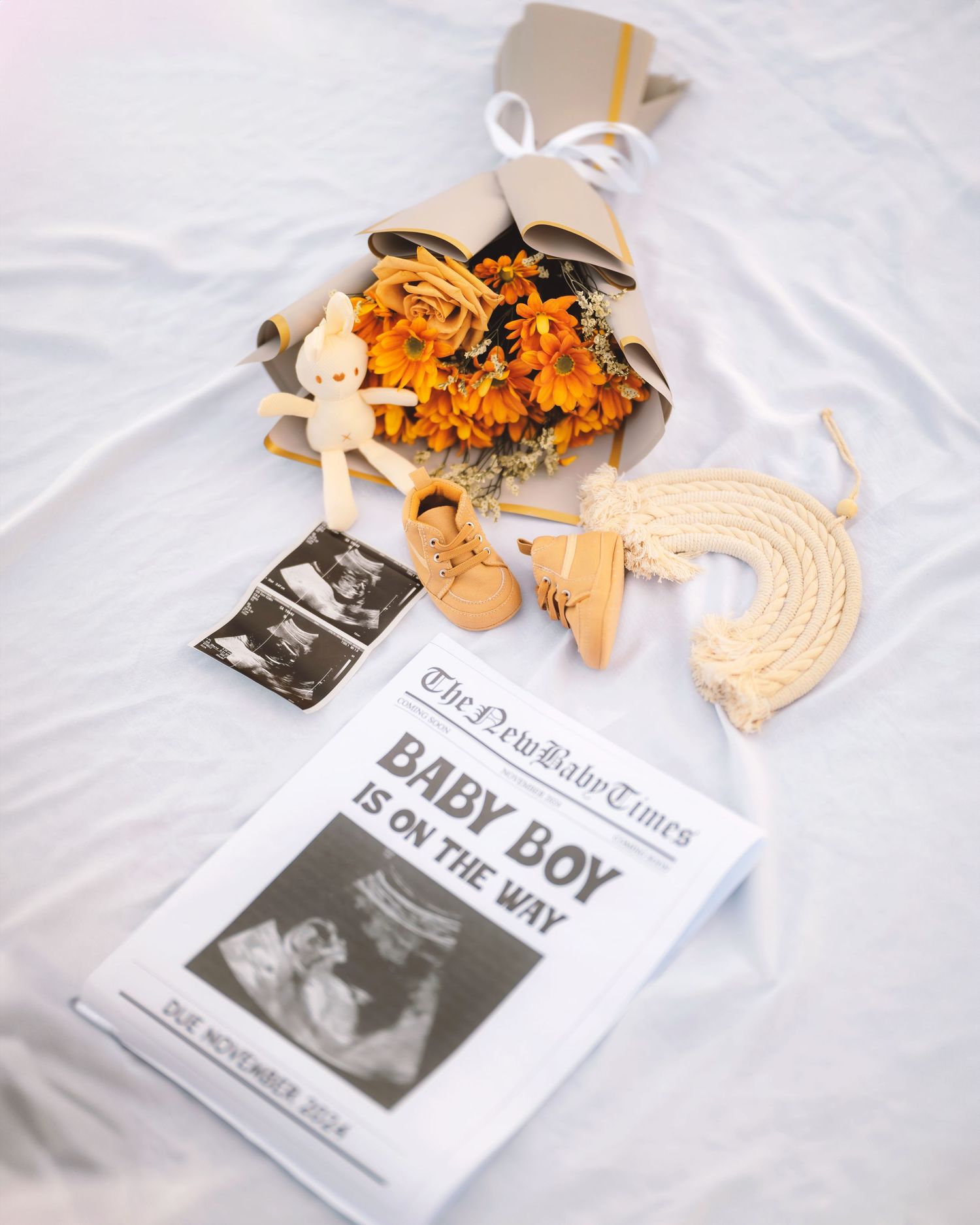 Baby announcement display with ultrasound photos, orange flowers, and decorative items.
