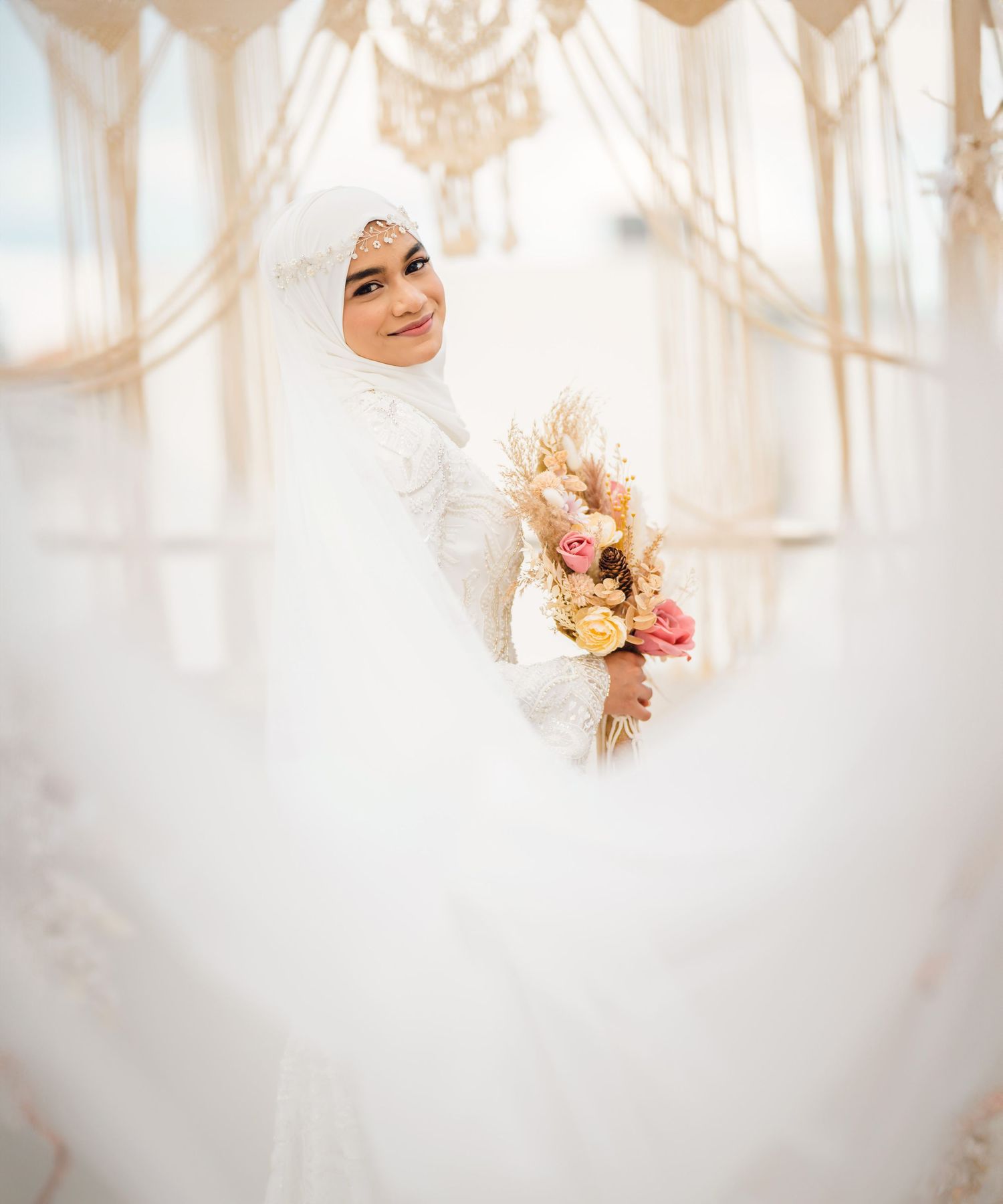 Ethereal bridal portrait with soft white lighting and delicate floral bouquet.