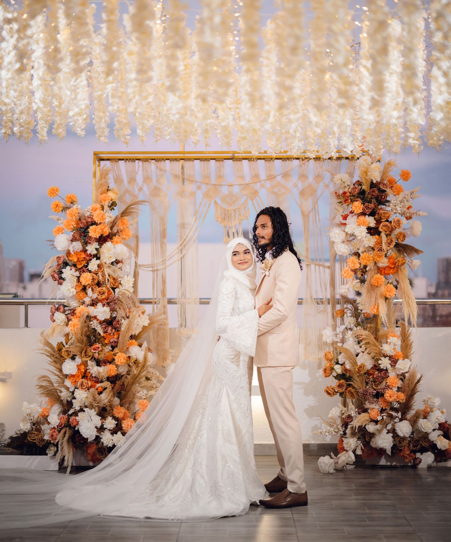 Wedding venue decorated with hanging crystal lights and orange floral arrangements.