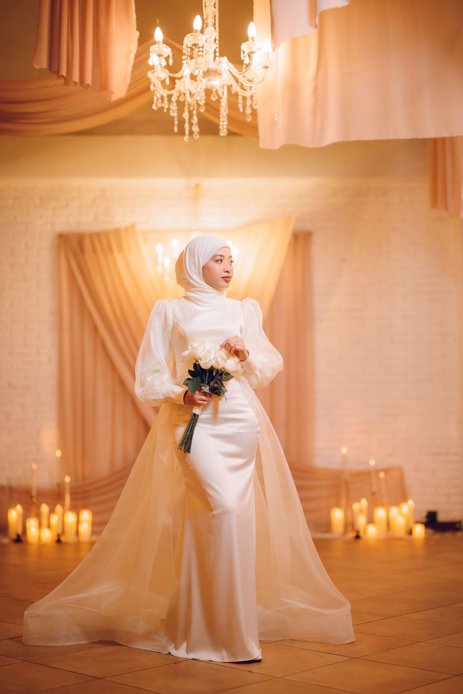 Candlelit wedding venue with flowing white drapes and crystal chandeliers creating a romantic ambiance.