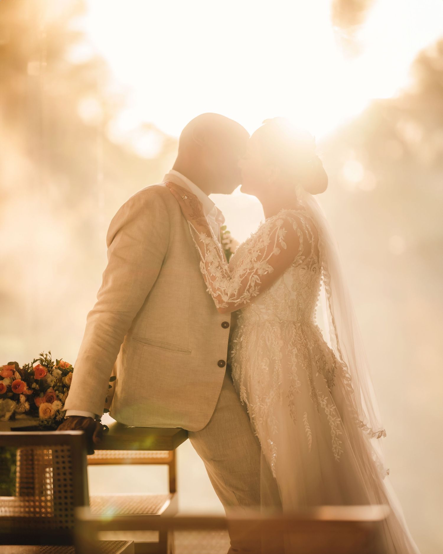 Dreamy backlit silhouettes of bride and groom standing together during golden hour.