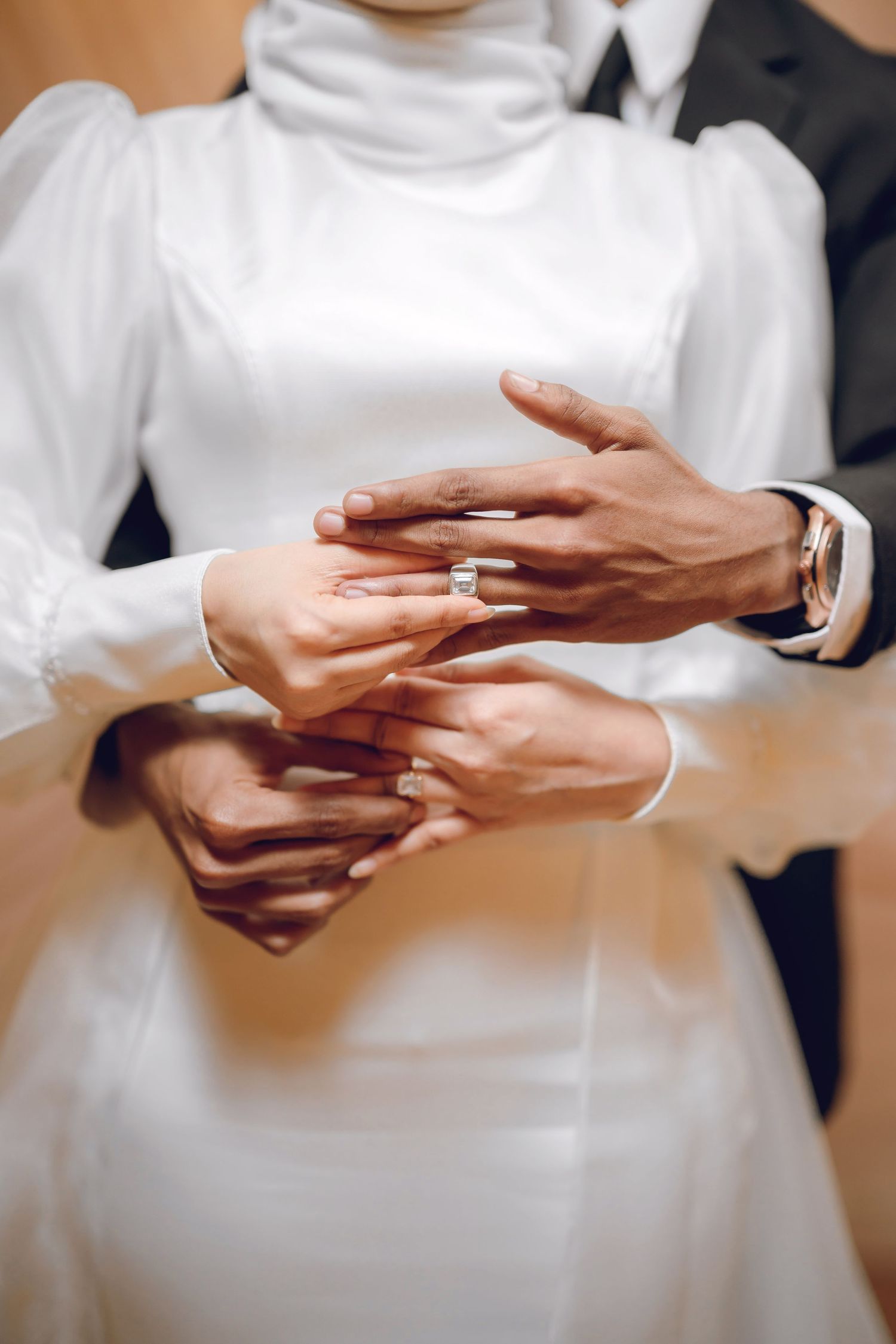 Close-up sequence of hands exchanging wedding rings during a traditional ceremony.