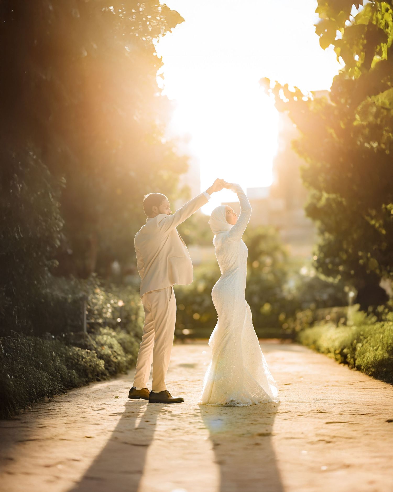 A couple dances together on a sunlit path during golden hour.